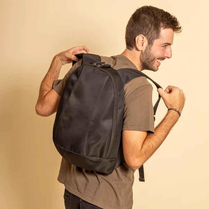 Man wearing a black arsayo nomade backpack against a beige background